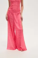 Pantalón largo de tela fluida con estampado de cebra en tonos rosa y fucsia. Tiene corte ancho y aberturas laterales con detalle de argollas.