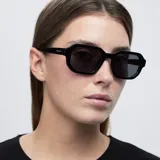 Lentes de sol con montura poligonal negra y lentes polarizadas negras. Protección UV400. Fabricados con material bio-based. Diseño equilibrado entre comodidad y durabilidad.