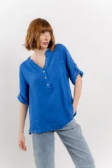 Camisa azul de lino con escote en V abotonado, bolsillo frontal y mangas 3/4 con trabilla.