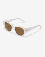 Gafas de sol Hawkers unisex, modelo Miranda, con montura color arena translúcido y lentes marrones.