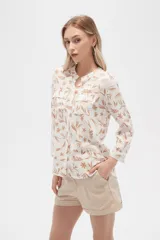 Camisa de viscosa con estampado floral en tonos azul, beige y blanco. Tiene cuello mao, mangas largas y bolsillos en el pecho.