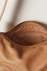 Bolso de hombro negro de cuero con correa fina y cierre superior.