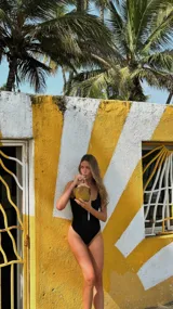 Traje de baño enterizo amarillo con textura arrugada, breteles finos y cierre marrón en el frente.