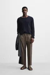 Pantalón de lino color marrón oscuro, de corte recto y relaxed fit. Tiene cintura elástica ajustable con cordón, bolsillos frontales y traseros de parche.