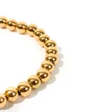 Pulsera de bolitas de acero enchapado en oro, con diseño delicado y elegante.