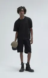 Remera negra de tejido de punto con moldería oversize, confeccionada en viscosa y poliéster. Presenta un diseño de malla con pequeños agujeros y un dobladillo acanalado.