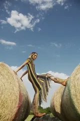 Vestido largo tejido al crochet con lurex, con diseño a rayas verticales en tonos beige y negro, y terminación con flecos.