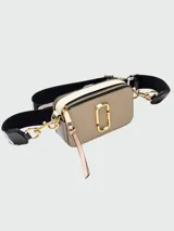 Bandolera Marc Jacobs modelo The Snapshot, color beige con logo dorado y correa ancha de tela negra con letras blancas.