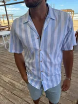 Camisa celeste y blanca a rayas verticales, de manga corta y corte recto.