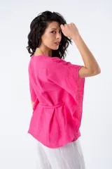 Blusa fucsia de viscosa, corte suelto, escote en V y mangas cortas tipo kimono. Incluye lazo del mismo material para ajustar a la cintura.