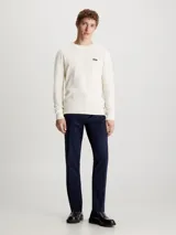 Sweater de punto color crema, de corte recto, con cuello redondo y logo de Calvin Klein en el pecho.