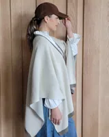 Ruana negra de tejido de punto con una estrella grande color beige en la espalda y borde inferior con franja beige.