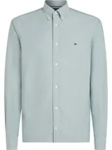 Camisa celeste de algodón Oxford, corte regular, con cuello abotonado, manga larga y logo de Tommy Hilfiger bordado en el pecho.