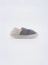 Pantuflas grises acolchadas con interior de felpa color crema y suela blanca.