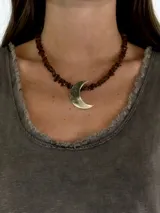 Gargantilla de cuentas color caramelo con dije de media luna dorada.