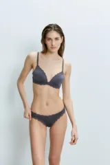 Conjunto de ropa interior color beige, compuesto por un corpiño triangulito de microfibra liviana con detalles de puntilla romántica, taza soft y breteles regulables, y una bombacha tipo colaless con cintura elástica y detalles de puntilla.