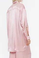 Camisa oversize de satén color rosa, con cuello camisero, manga larga con abertura en puño, cierre frontal con botones y bolsillos en el pecho.