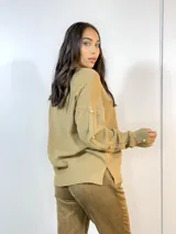Sweater color camel de tejido de punto con cuello redondo y mangas largas. Presenta detalle de botones dorados en los puños y en los hombros.