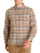Camisa de franela a cuadros azul, beige y negro, de manga larga con puños abotonados, cuello camisero y cierre frontal con botones de madera. Tiene dos bolsillos de parche con botón en el pecho. Confeccionada en algodón orgánico cepillado.
