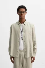 Camisa color arena de lino con cuello abotonado, manga larga con puños abotonados, corte regular y bajo con aberturas laterales.