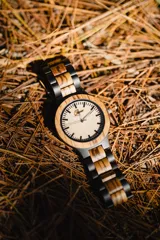 Reloj de pulsera con caja y esfera de madera clara, malla de madera oscura con incrustaciones de madera clara.