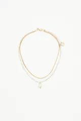 Collar doble, uno dorado y otro plateado, con dije de cristal transparente en forma de corazón.