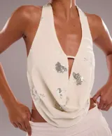 Top blanco con estampado floral plateado, escote halter y cierre frontal con cordones.