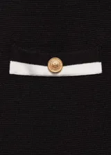 Pantalón negro de punto fino con diseño recto y largo, tiro medio, cintura elástica, ribetes en contraste y bolsillos de ribete delanteros con botones decorativos.