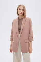 Blazer color rosa viejo, de corte recto, con solapas y mangas 3/4 con botón decorativo.