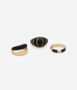 Set de tres anillos dorados con detalles esmaltados en negro. Incluye un anillo con diseño circular, otro con forma de lágrima y un tercero liso.