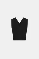 Top negro confeccionado en tejido de punto con escote pico, tirantes anchos cruzados en la espalda, detalle de drapeado en hombros y aplicación de hombreras.