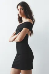 Vestido corto negro de tejido de punto, con escote recto y hombros descubiertos.