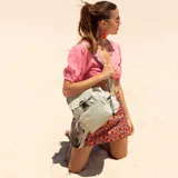 Mochila gris de nylon con tapa y broche metálico, apertura superior con cierre marinero, bolsillos internos, bolsillo con cierre metálico al frente y laterales, asas rígidas de mano y correas regulables para colgar en la espalda.