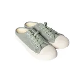 Zapatilla urbana color verde con cordones y suela blanca.