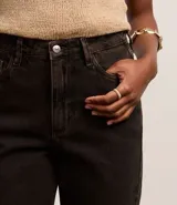 Pantalón wide leg de sarga color negro, con cintura alta, bolsillos delanteros y traseros, cierre con botón y cremallera, y trabillas para cinturón.