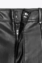 Pantalón marrón de tiro alto con efecto cuero, bolsillos de parche en la parte trasera y costuras marcadas en la parte delantera. Cierre frontal con cremallera y gancho metálico.