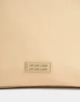 Bolso tipo shopper color beige con doble asa corta de hombro, cierre superior y tag de goma con logo.