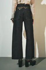 Pantalón de jean de tiro alto color negro con pierna ancha, bolsillos delanteros y traseros, y cierre frontal con cremallera y botón metálico.