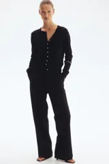 Saco de punto negro con cuello redondo y botones dorados. Tiene remate acanalado en cuello, puños y bajo.