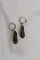 Par de aros colgantes con argolla de acero quirúrgico hipoalergénico y dije en forma de gota de piedra natural color marrón con vetas.