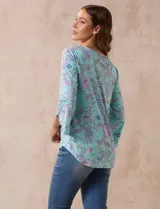 Blusa de seda fría estampada con flores en tonos celeste, lila y verde. Tiene cuello redondo con escote en V entrelazado y mangas 3/4 acampanadas.