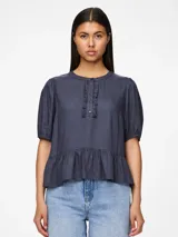 Blusa azul de mangas 3/4 con cuello redondo, botones y volantes.