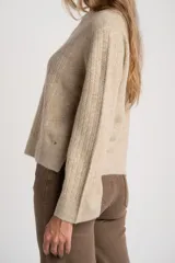 Sweater de punto color beige melange, con cuello redondo y manga larga. Presenta un tejido texturado con relieve vertical.