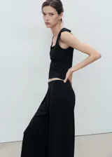 Top sin mangas color negro, de tejido elástico y diseño entallado, con escote cuadrado y tirantes anchos.