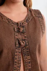 Chaleco de denim negro sin mangas con cuello redondo y costuras en contraste. Presenta un parche de cuero marrón en la parte posterior con el logo de la marca Be Ganesha. Confeccionado en tejido de algodón.