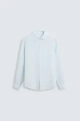 Camisa celeste de lino, de corte recto, manga larga con puños abotonados y cuello clásico.