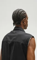 Camisa negra sin mangas de calce oversize con doble bolsillo y detalle de remaches en el frente, confeccionada en tejido twill de alta calidad.