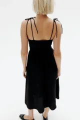Vestido midi negro con cuerpo entallado fruncido, escote redondo y breteles spaghetti. Costura fruncida en la cintura y pollera con leve vuelo.