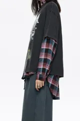 Camiseta de algodón negra, corte oversize, con cuello redondo. Presenta un estampado gráfico grande en el frente que incluye el texto "BIMBAYLOLA", dos lobos en una nube y un paisaje con relámpagos.