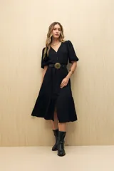 Vestido midi negro con botones frontales, mangas cortas abullonadas, escote en V y falda con volantes. Incluye cinturón negro con hebilla dorada.